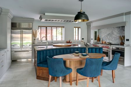 A bespoke shaker kitchen with an integrated round table, surrounded by blue chairs.