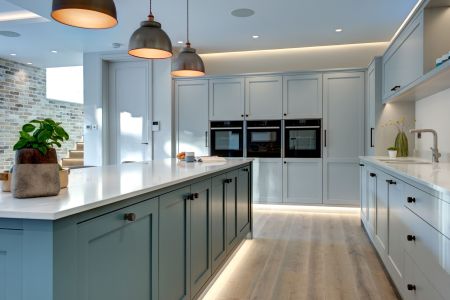 A large, bespoke shaker kitchen with a kitchen island, featuring under-counter lighting.