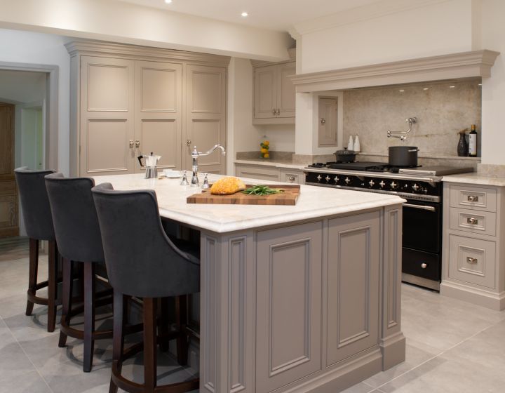 A large, bespoke traditional kitchen with a centre island with a cutting board on it.