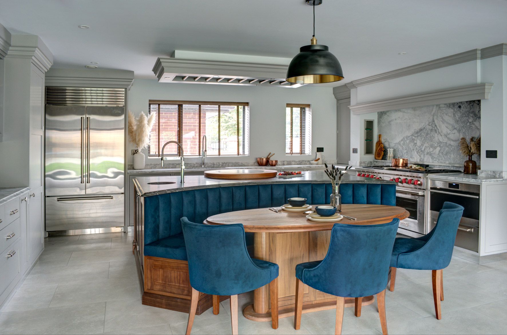 A bespoke shaker kitchen with an integrated round table, surrounded by blue chairs.