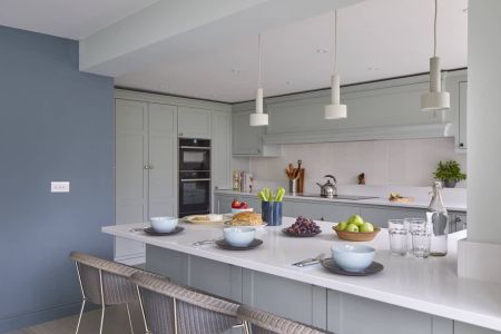 A bespoke shaker kitchen with blue walls and white counter tops.