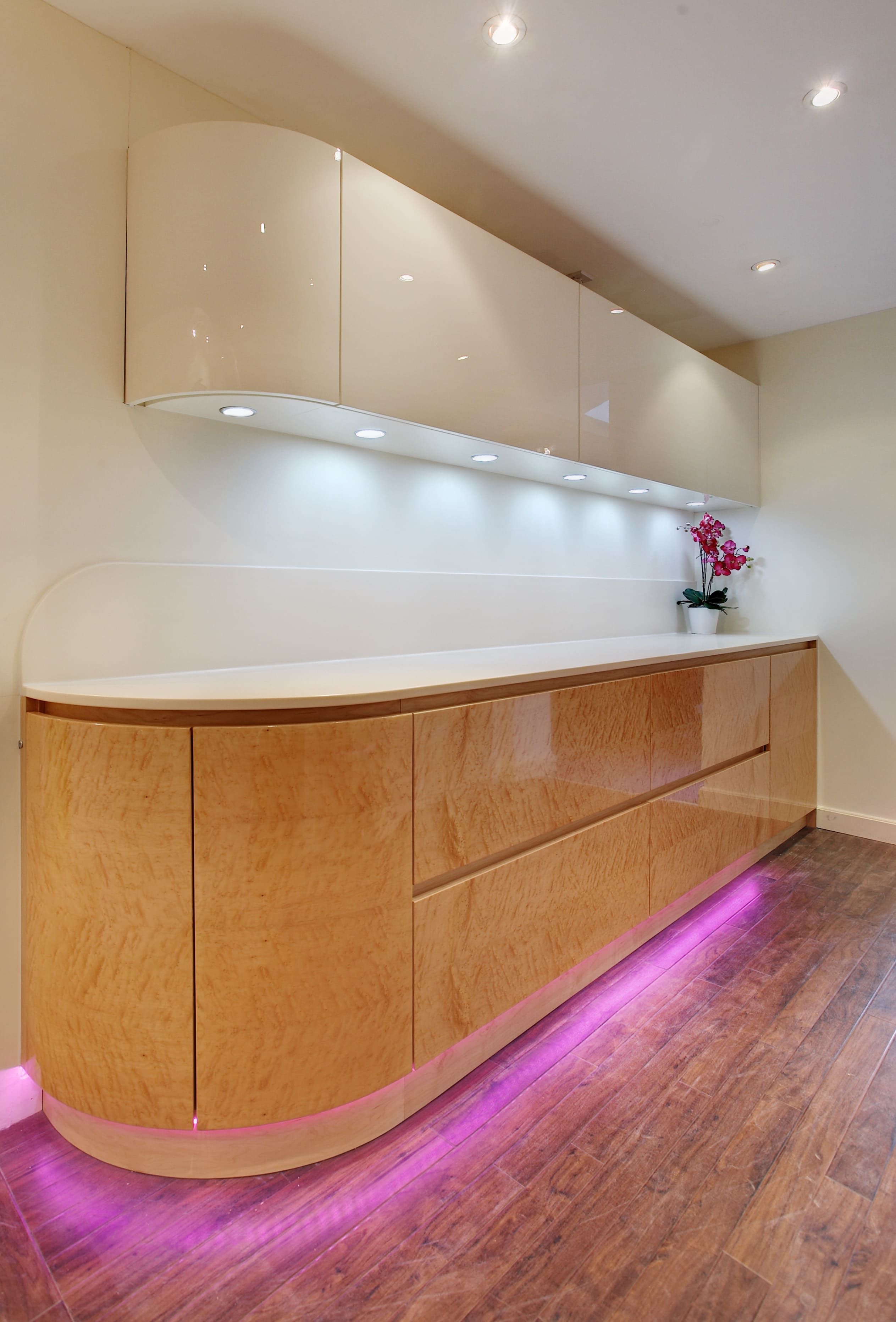 A bespoke contemporary, varnished wood corner countertop, featuring some under-counter lighting.