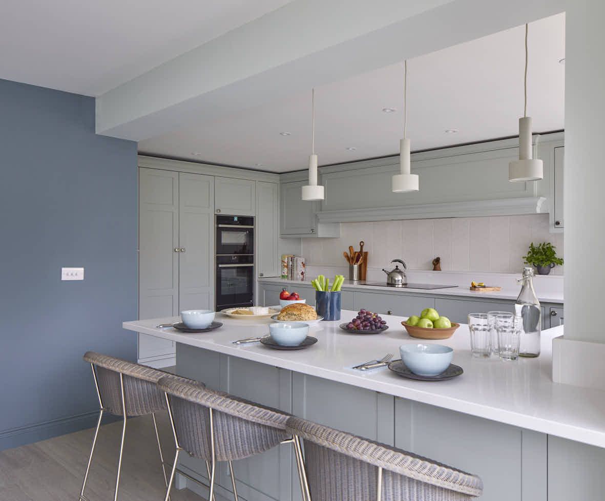 A bespoke shaker kitchen with blue walls and white counter tops.