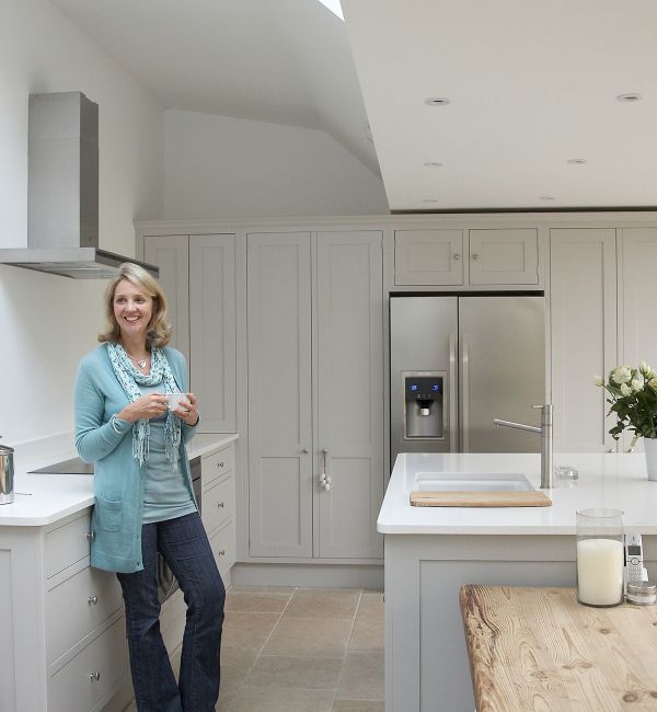 A woman can be seen smiling while stood in her new bespoke Shaker kitchen from Stonehouse.