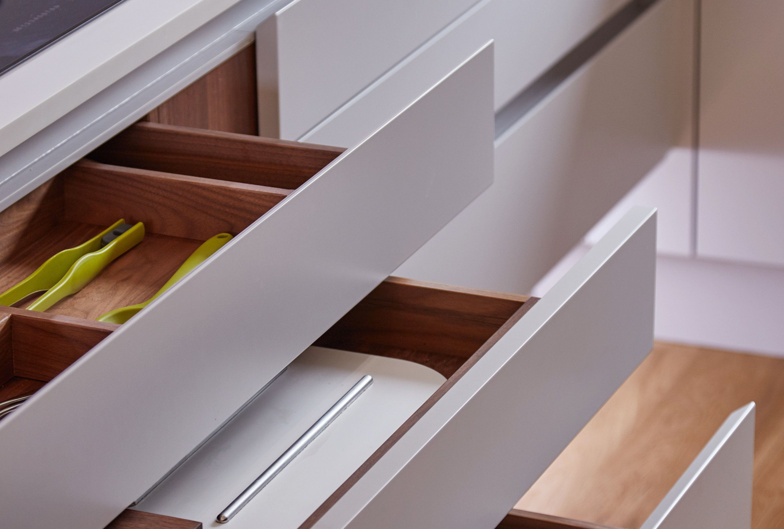 A series of drawers are opened in step, showing the precision finish of the bespoke kitchen from Stonehouse Furniture.