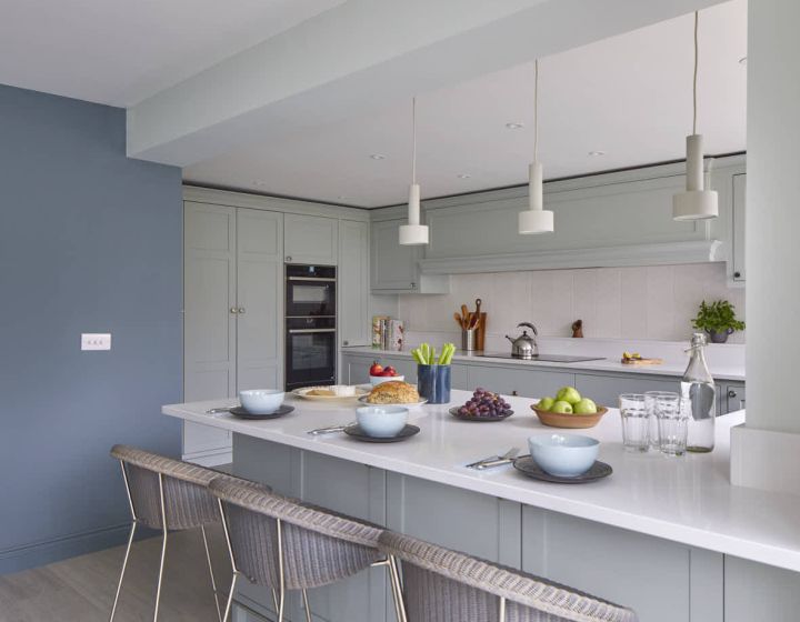 A bespoke shaker kitchen with blue walls and white counter tops.