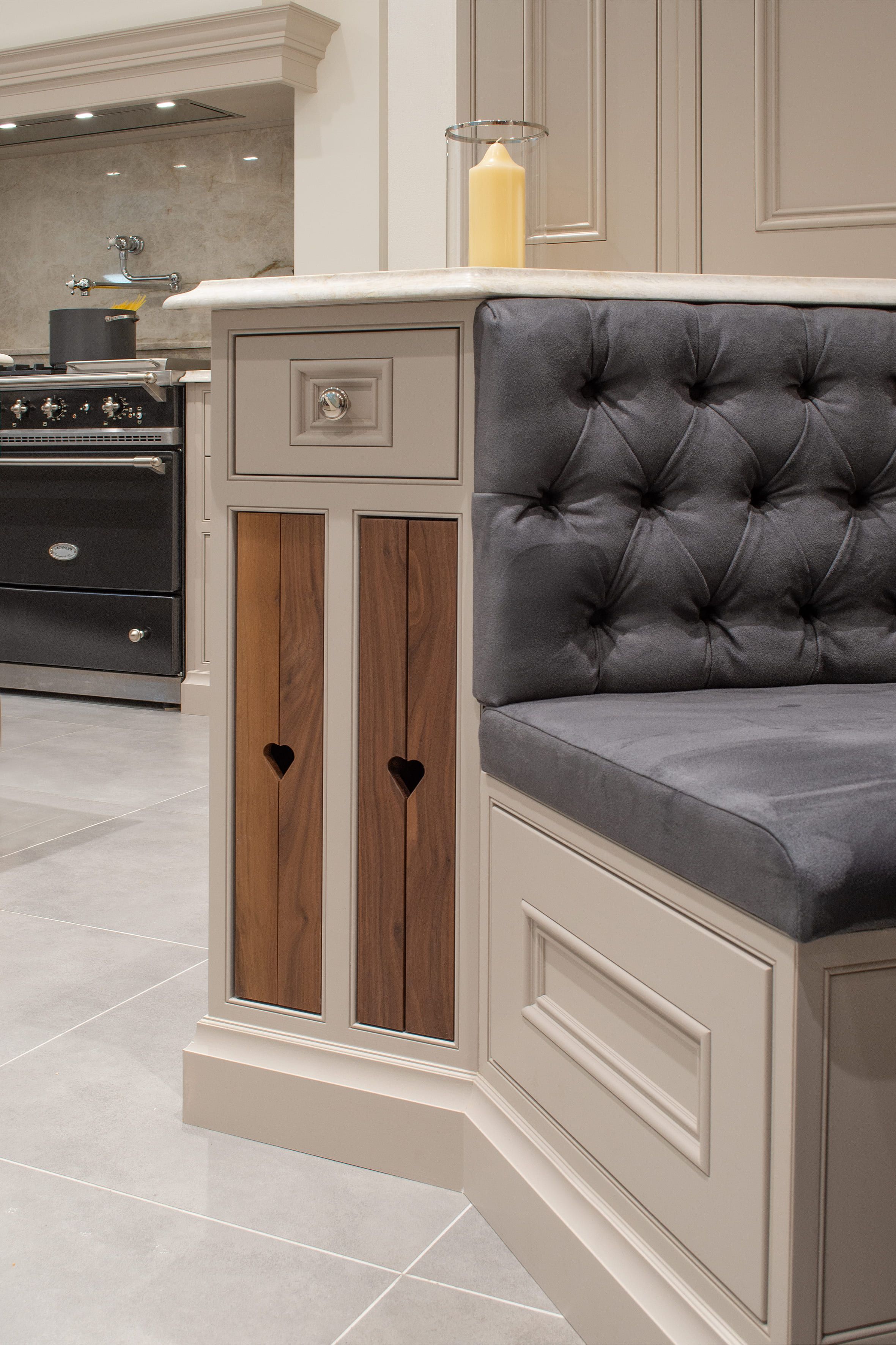 A bespoke bench seat with built-in cabinets and drawers. In the background a large, integrated range cooker can be seen 