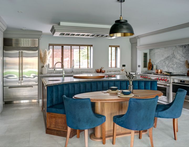 A bespoke shaker kitchen with an integrated round table, surrounded by blue chairs.