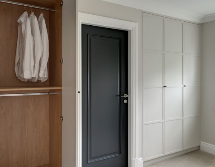 A minimalist bespoke dressing room. Grey cabinets line the wall, one is opened to show the functionality of the room.